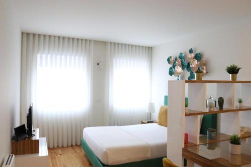 Schlafzimmer mit einem Bett und einem Schreibtisch mit einem TV in der Unterkunft ORM - São Lazaro Apartment in Porto