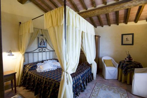 a bedroom with a canopy bed and a chair at Agriturismo Il Macchione in Pienza