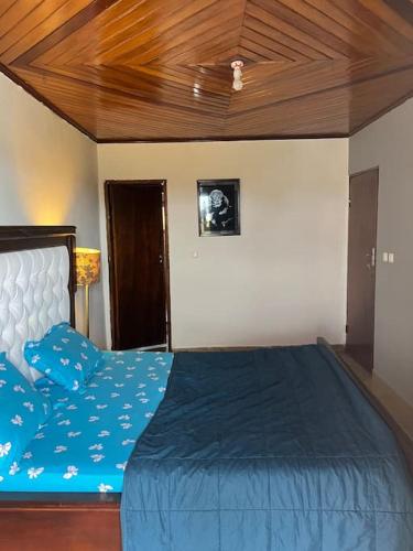 a bedroom with a blue bed with a wooden ceiling at AU COEUR DE BONAMOUSSADI-WIFI-PARKING-GARDIENS-24H in Douala