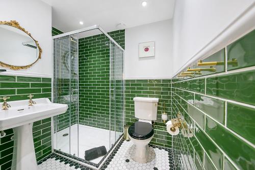 a green tiled bathroom with a toilet and a sink at Market Street Apartments ✪ Grampian Lettings Ltd in Aberdeen