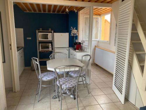 une cuisine avec une table, des chaises et un réfrigérateur dans l'établissement Joli appartement mezzanine avec parking et wifi La Roquille, au Cap d'Agde