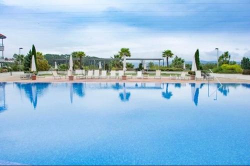 una grande piscina blu con sedie e alberi di RESIDENCIAL ILLAS ATLANTICAS en SANXENXO a Portonovo