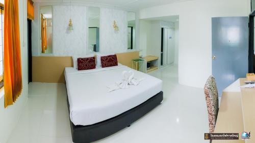 a bedroom with a bed with white sheets and red pillows at The Train Hotel Hatyai in Hat Yai