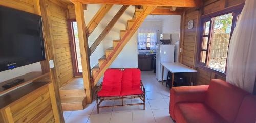 uma sala de estar com uma cadeira vermelha numa casa em Chalés Rota do Sol Praia do Rosa em Praia do Rosa