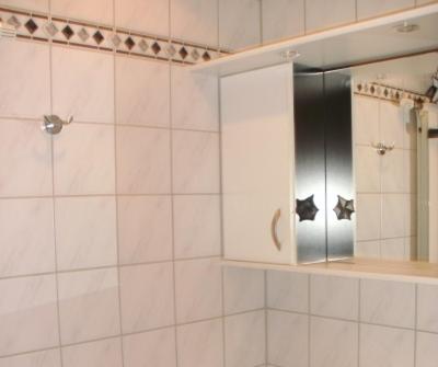 a white tiled bathroom with a shower with a mirror at Haus Gartnerkofelblick in Kirchbach