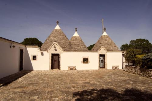 a large white building with three pointed roofs at Trulli Cibelis in Noci