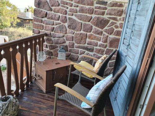 a porch with two chairs and a table and a stone wall at Casamia4u in Alsóörs
