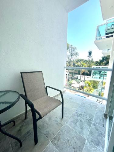 a room with a chair and a glass table and a balcony at Gran Palma Residencial in Acapulco