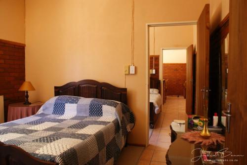 a bedroom with a bed with a checkered blanket at Mieliefontein Karoo Guest Farm in Hanover Road