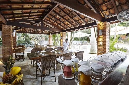 un homme debout sur une terrasse avec des tables et des chaises dans l'établissement PortoBay Búzios, à Búzios