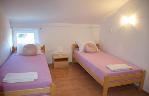 two beds in a small room with a window at Apartments Summer Joy in Novalja