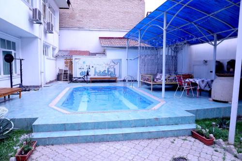 a swimming pool with a blue umbrella in a backyard at Art Hostel in Tashkent