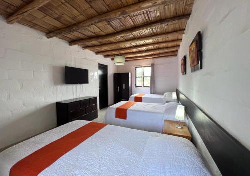 a bedroom with two beds and a television in it at La Estancia Chincha Hotel in Chincha Alta