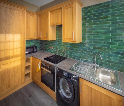 a kitchen with a sink and a washing machine at Spacious 1st Floor Apartment in Keswick
