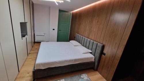 um pequeno quarto com uma cama e uma porta verde em MESHI APARTMENT em Durrës