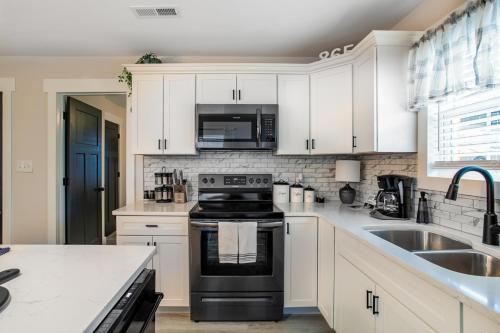 a kitchen with white cabinets and a black stove top oven at Blue Valley Inn - Hot Tub & Spacious Play Area! in Knoxville