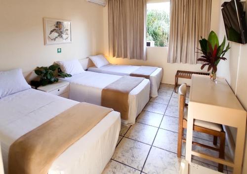 a hotel room with two beds and a table at Hotel Harbor Inn Londrina in Londrina