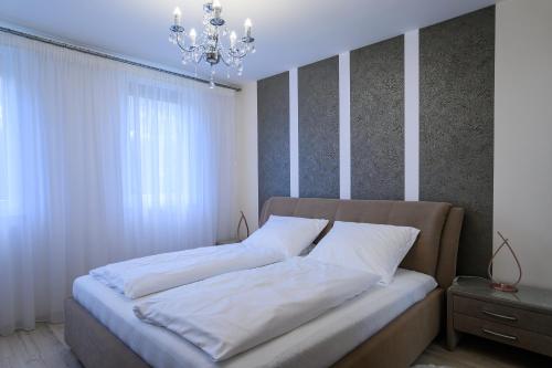 Schlafzimmer mit einem Bett mit weißer Bettwäsche und einem Kronleuchter in der Unterkunft Perczel Apartman in Balatonfüred
