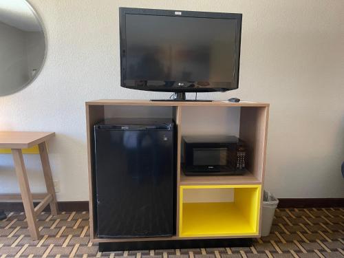 a tv on top of a tv stand with a microwave at Days Inn by Wyndham Fayetteville-South/I-95 Exit 49 in Fayetteville