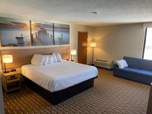 um quarto de hotel com uma cama e um sofá azul em Days Inn by Wyndham Fayetteville-South/I-95 Exit 49 em Fayetteville