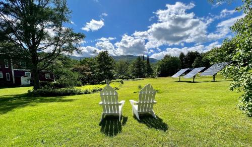 zwei weiße Stühle im Gras auf einem Feld in der Unterkunft The Griff Inn in Waitsfield