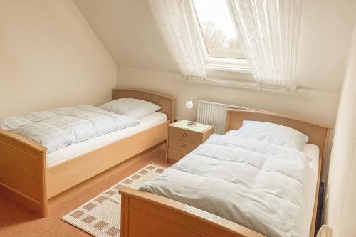 two beds in a small bedroom with a window at Ferienwohnungen Schierbaum in Lembruch