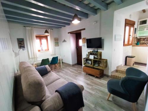 sala de estar con sofá, sillas y TV en Casa Pangea en Vejer de la Frontera