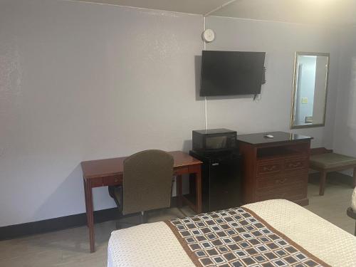 Dormitorio con escritorio, cama y TV en Economy Inn Little Rock, en Little Rock