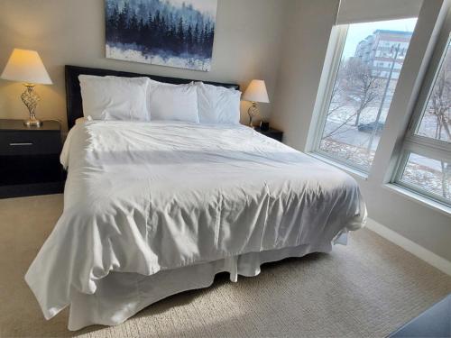a bedroom with a large white bed with two windows at The North End Apartments in Milwaukee