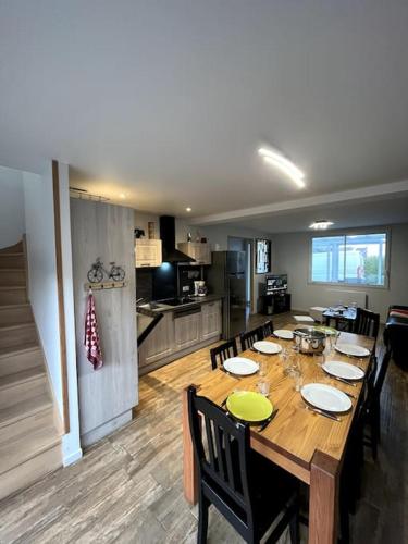 une grande table en bois avec des chaises et une cuisine dans l'établissement Gîte équipé 1 à 8 personnes modulable lire hôte, à Montfarville