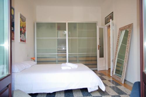 um quarto com uma cama branca e um espelho em Incantevole Appartamento De Angeli em Milão