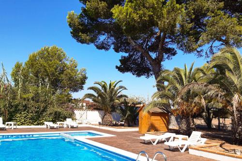 una piscina con sillas blancas y árboles en Viviendas turísticas Lesley VTV Es Pi - Formentera Break, en Playa de Migjorn
