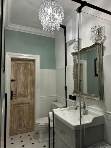 a bathroom with a chandelier and a sink and a toilet at Orlicz 32 Apartments in Zamość