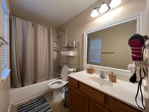 y baño con lavabo, aseo y espejo. en Cozy 3-bed Garden Home - 10 mins to UT Stadium and Downtown Austin, en Austin