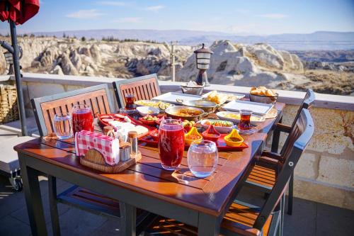 Cappadocia Sweet Cave Hotel في نوشهر: طاولة عليها طعام ومشروبات مطلة