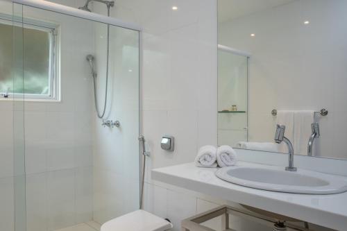 uma casa de banho branca com um lavatório e um chuveiro em O HOTEL em Búzios