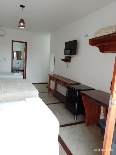a room with two beds and a desk and a television at Pousada Morada do Sol in Camocim