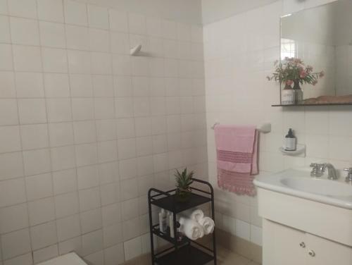 Baño de azulejos blancos con lavabo y espejo en Lo de Poujade en Posadas