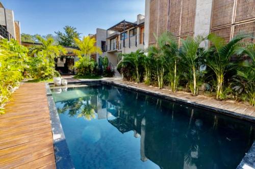 a swimming pool in front of a building with a house at Apartamento Moderno en Tulum Quintana Roo México in Tulum