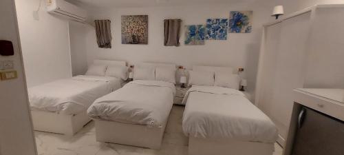 três camas num quarto com paredes brancas em White House em Aswan