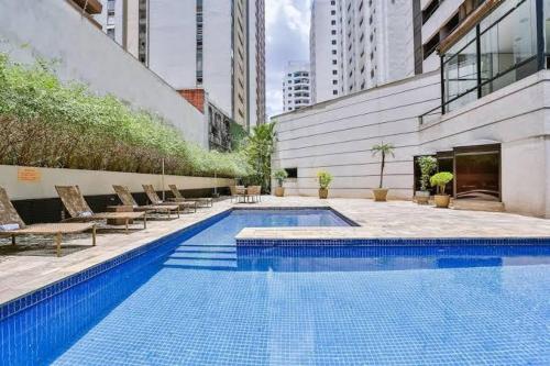 una gran piscina con sillas y un edificio en Flat em Hotel 4 estrelas - Alameda Lorena, en São Paulo
