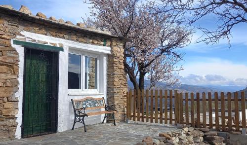 a bench sitting outside of a building with a window at Cortijo La Vista in Órgiva