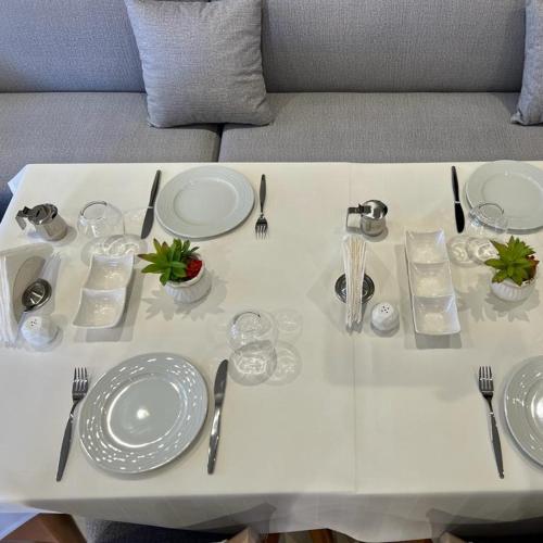 a white table with plates and utensils on it at Hotel Mimani in Berat