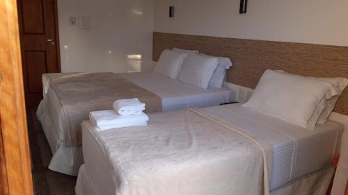 two beds in a hotel room with towels on them at Pousada Morada do Sol in Camocim
