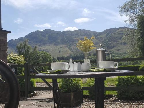 a table with a tea set on it with mountains in the background at Achray House Restaurant with Rooms in Saint Fillans