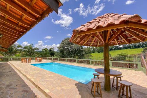 einen Pool mit einem Tisch und einem Sonnenschirm in der Unterkunft Chacara com churrasq, piscina e lazer - Socorro SP in Socorro