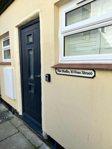 a house with a black door and a sign on it at The Studio, Foss Street, Central Dartmouth in Dartmouth