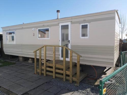 a white trailer with a ramp next to a fence at Caravan 2 bedroom - New Camping Ideal in De Haan