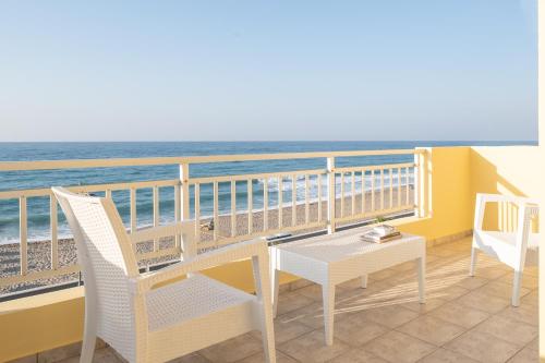 a balcony with a table and chairs and the ocean at Unique seaside apartment in Rethymno Town