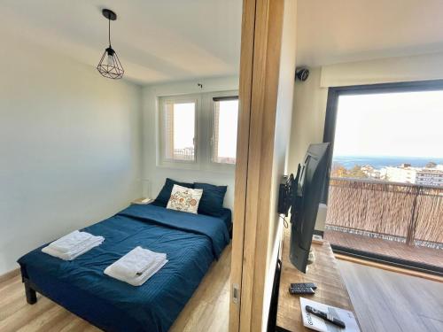 Schlafzimmer mit einem Bett, einem TV und einem Balkon in der Unterkunft Le Turgot, proche thermes in Thonon-les-Bains